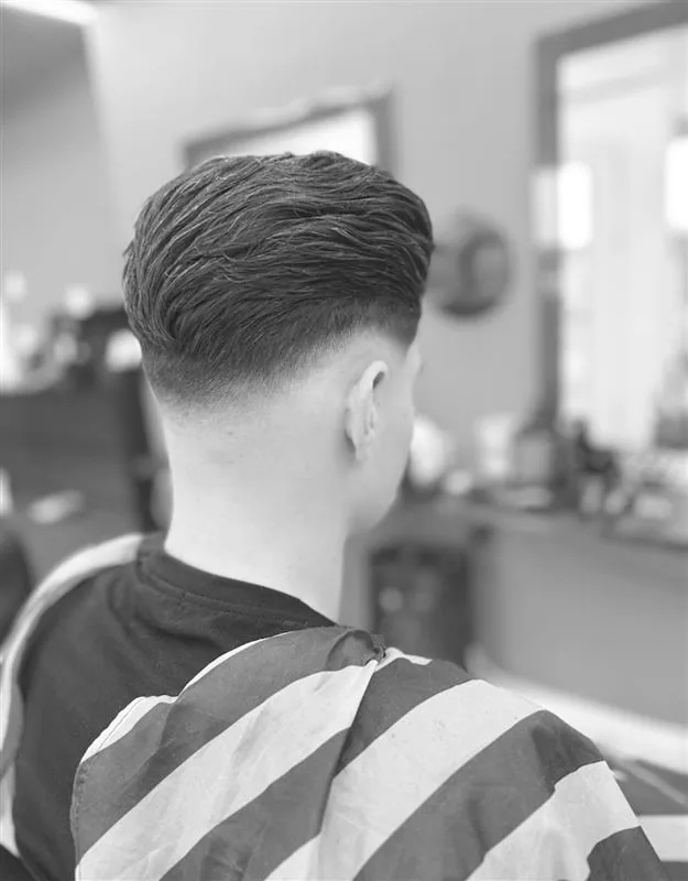 Low Fade mit Textur am Oberkopf, geschnitten bei UNO Coiffeur